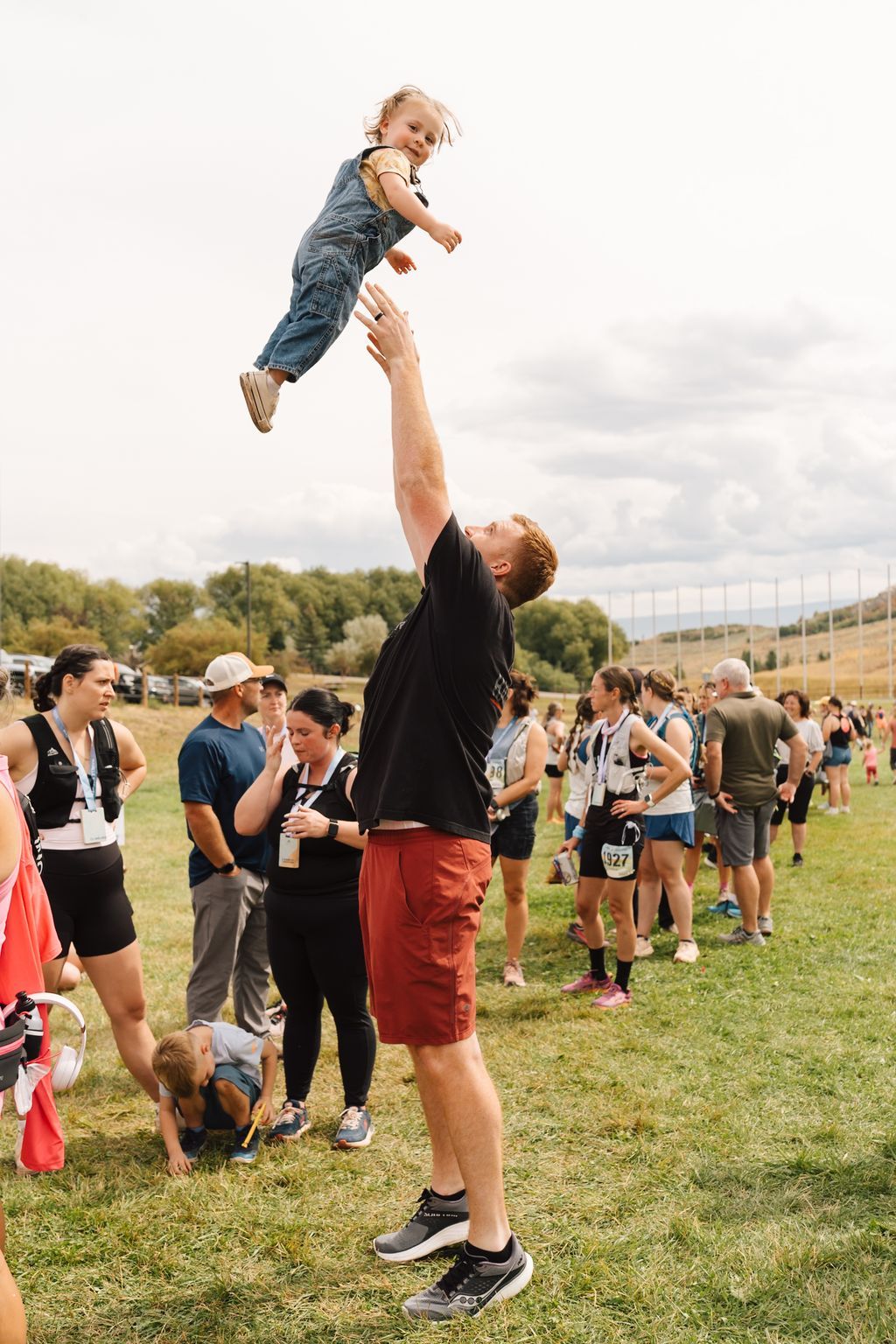 A dad tossing a baby in the air in the finish line field.