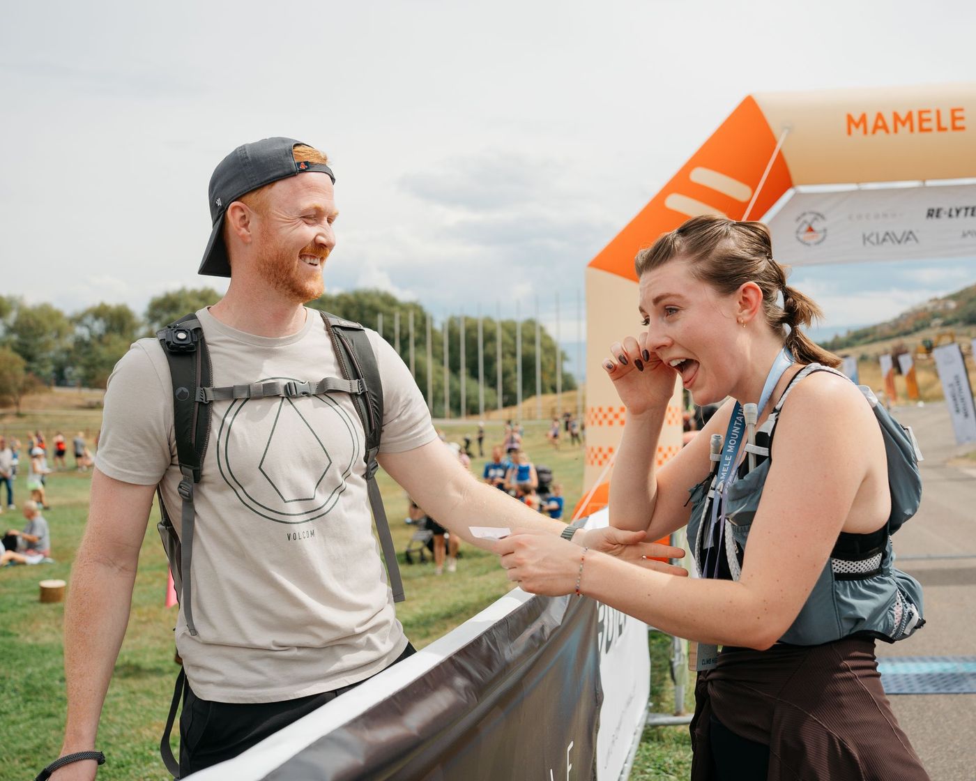 A racer being handed something at the finish line by a volunteer.