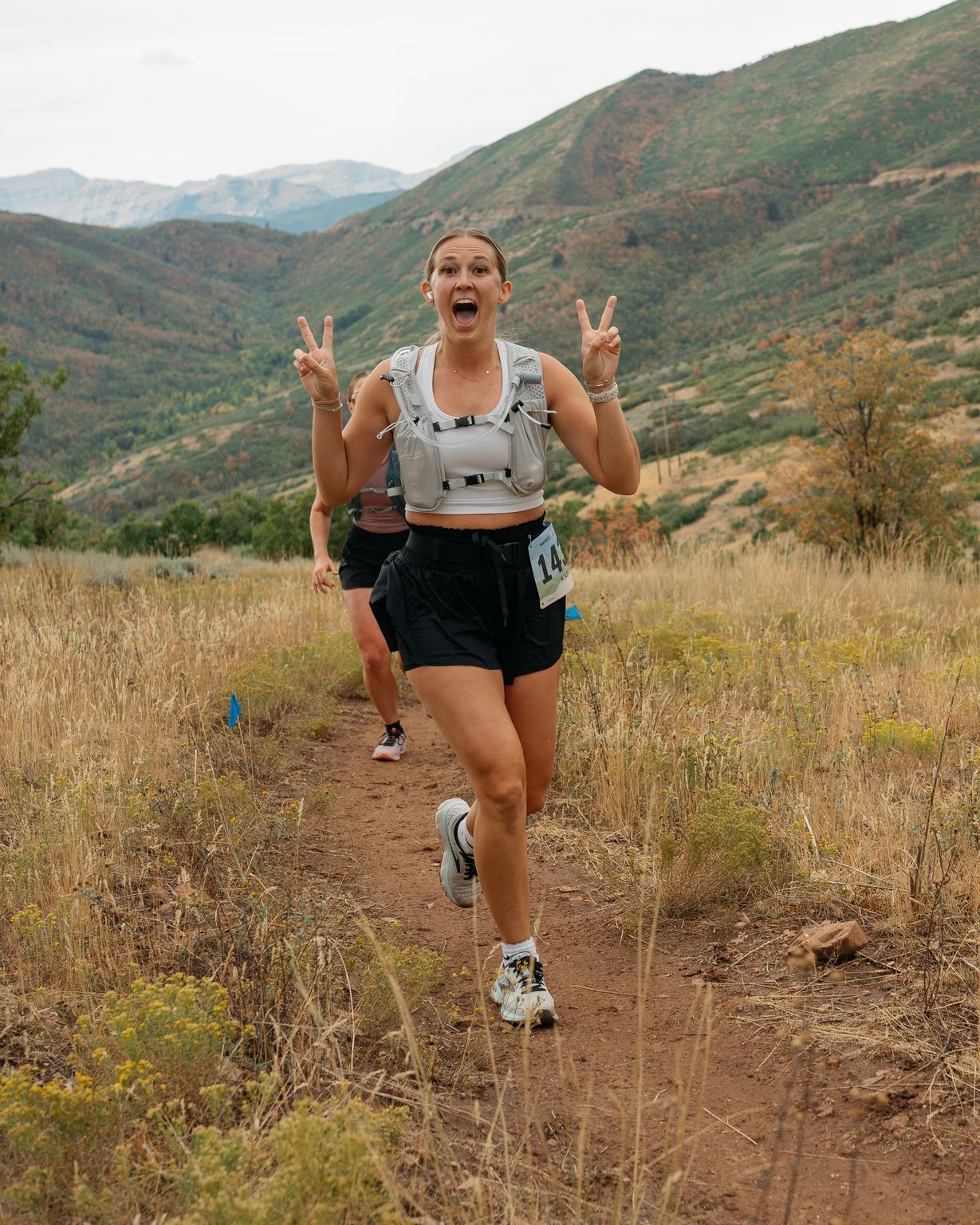 Two runners jumping in the air together on the road, arms out.