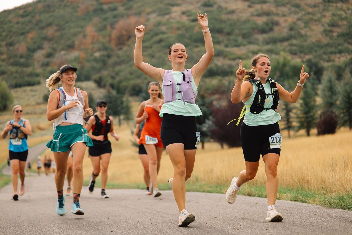 Three runners finishing side by side with arms raised.